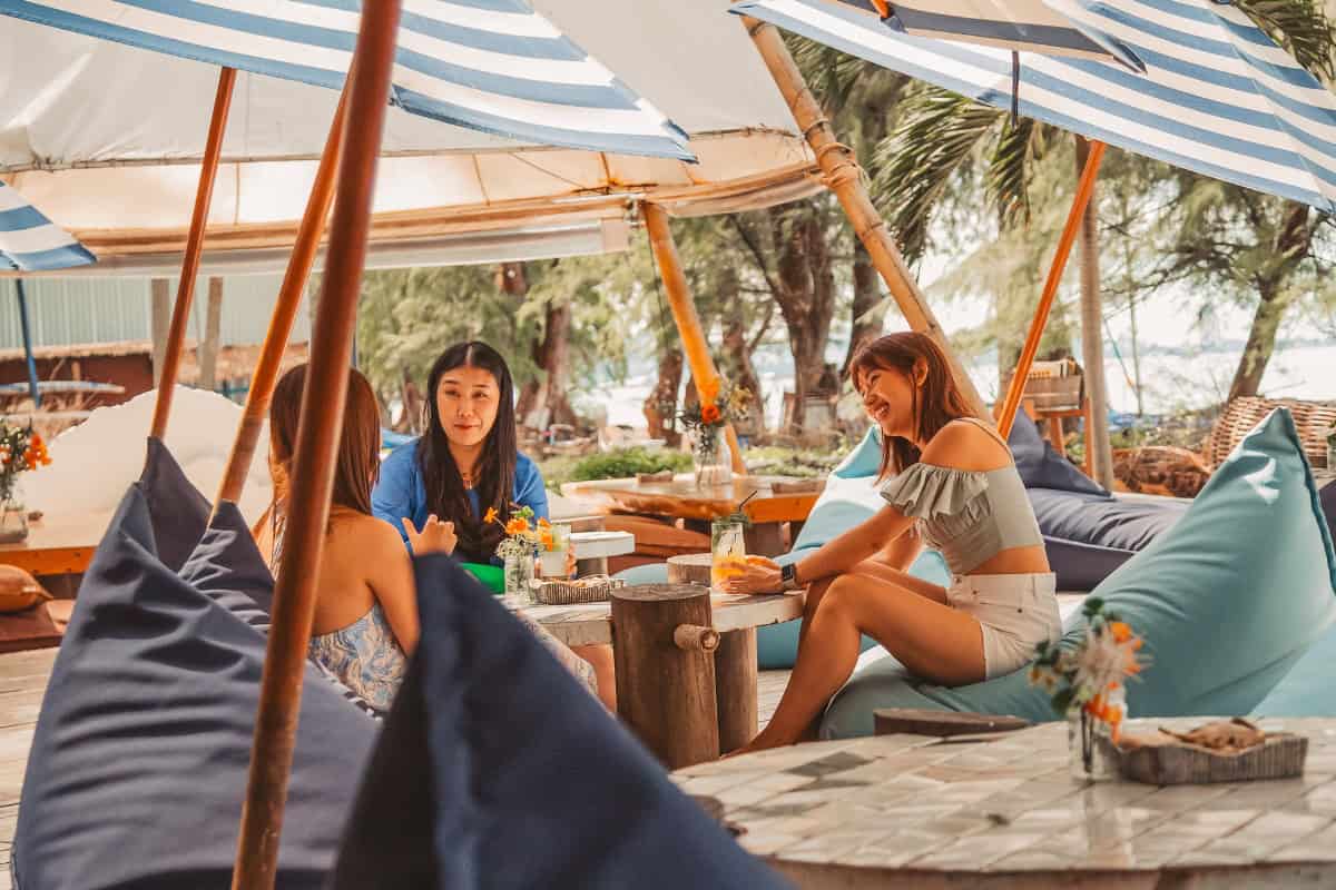 group of friends enjoying drinks under umbrellas at cave seaside restaurant in pattaya